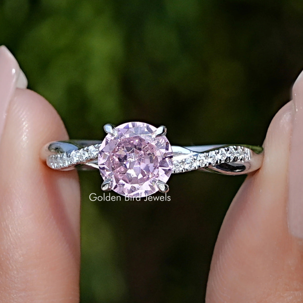 Front view of Pink Tourmaline Round Gemstone Accent Ring in two fingers 