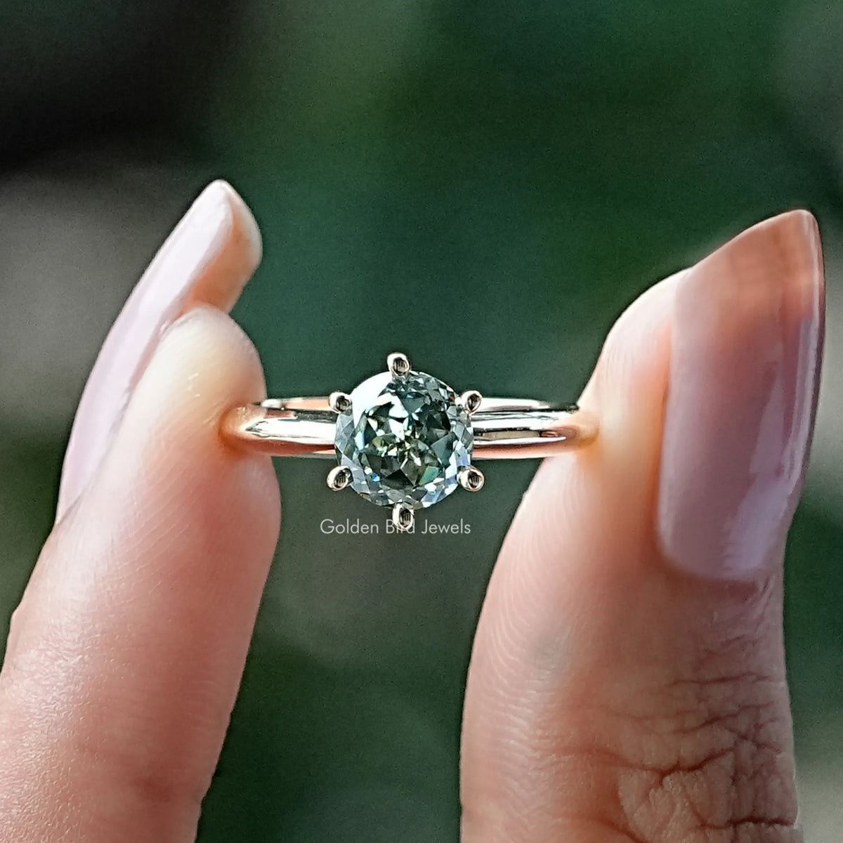 Two fingers holding the Portuguese Round Cut Solitaire Ring