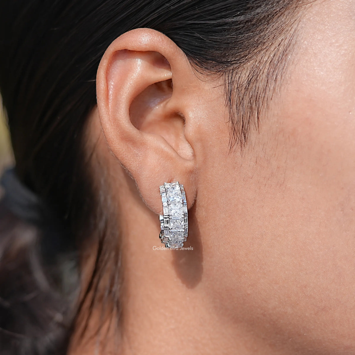 Close-up view of a woman's wearing a princess-cut moissanite C-hoop earrings.