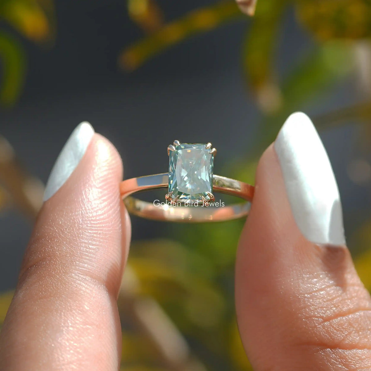 Front View Of Radiant Cut Moissanite Engagement Ring In a two fingers
