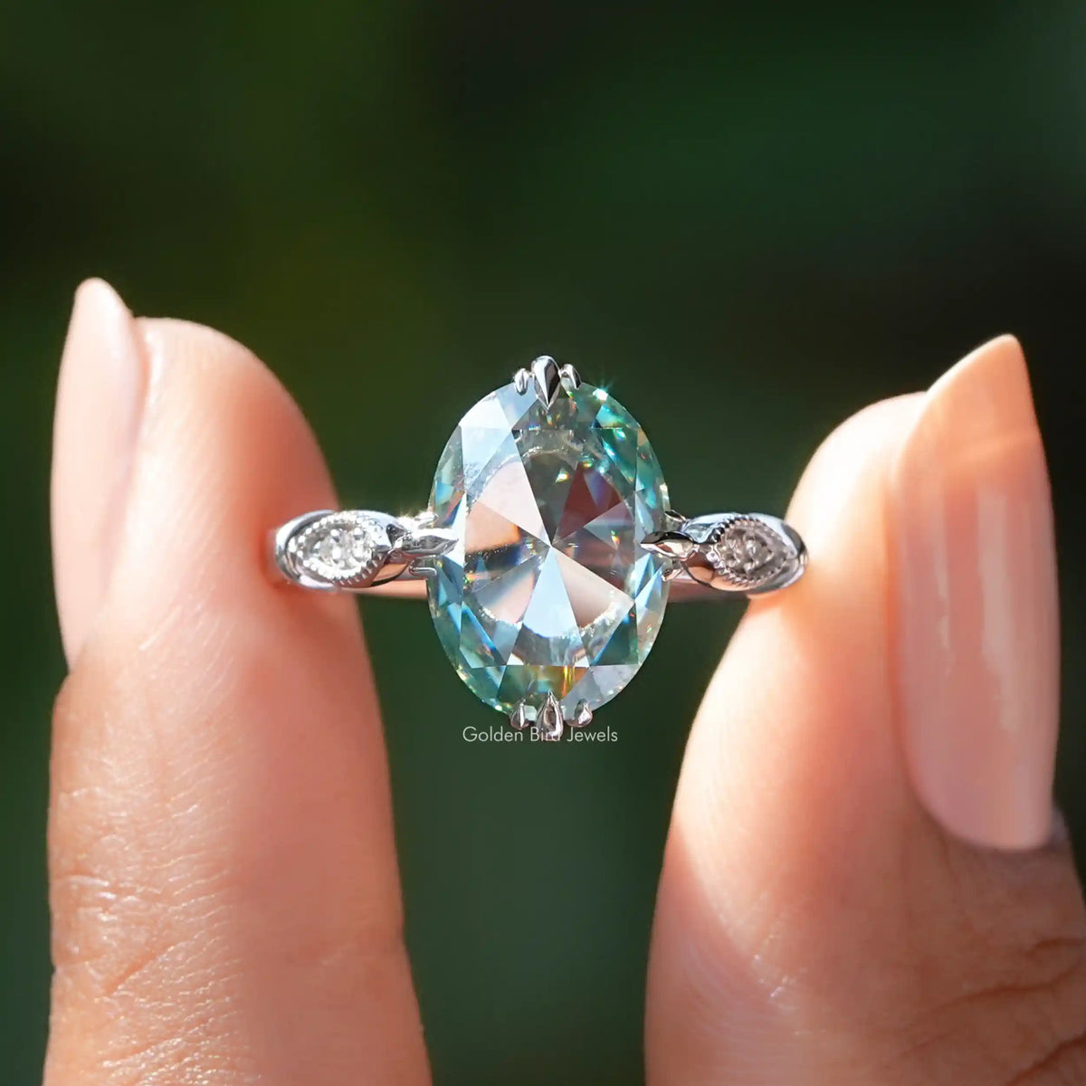 Rose oval cut moissanite accent ring held on two fingers.
