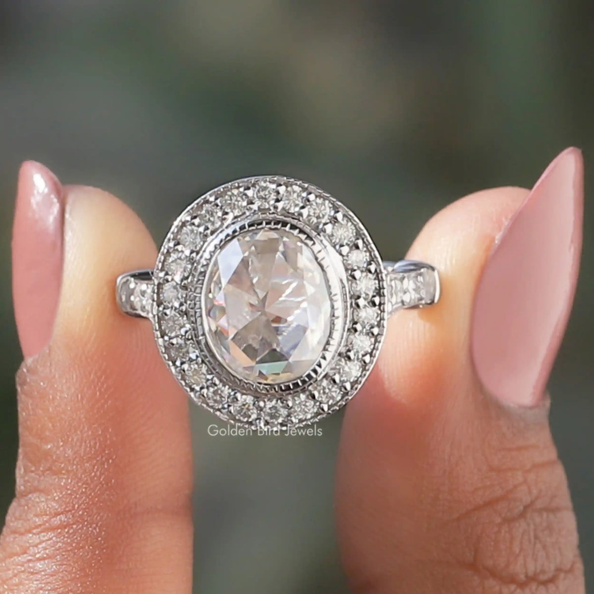 Two fingers holding the Rose Cut Oval Moissanite Halo Engagement Ring 