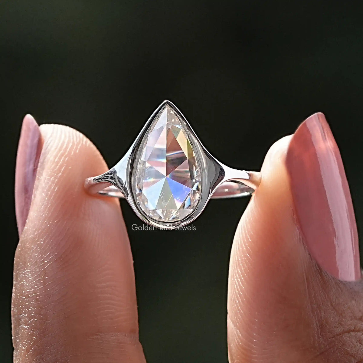 Two fingers holding the Rose Cut Pear Moissanite Bezel Set Ring