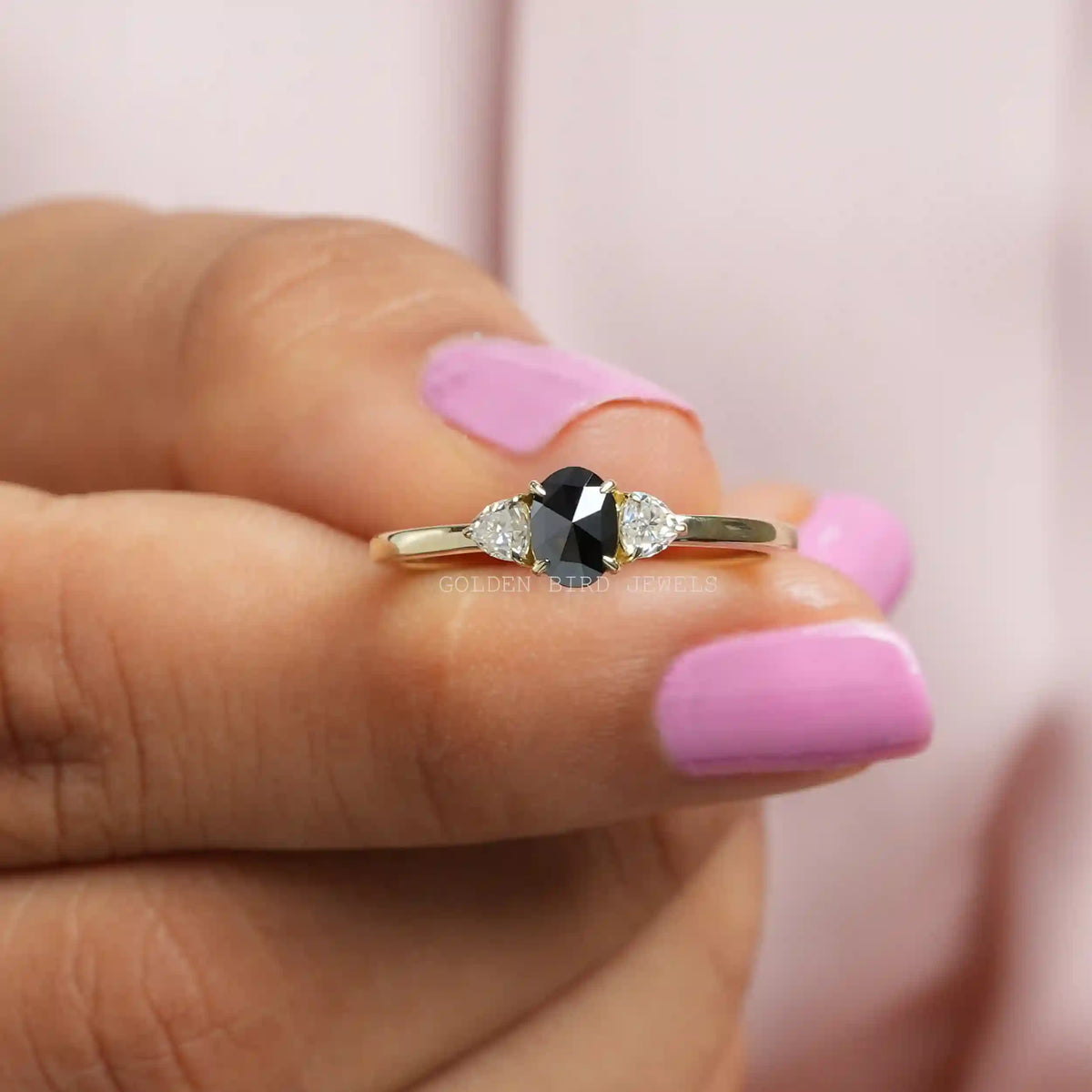 Two fingers holding the 3 Stone Oval Rose Cut Moissanite Ring