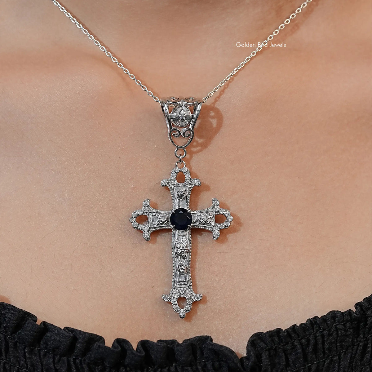 Silver-tone cross pendant necklace with dark round gemstone center and side accents