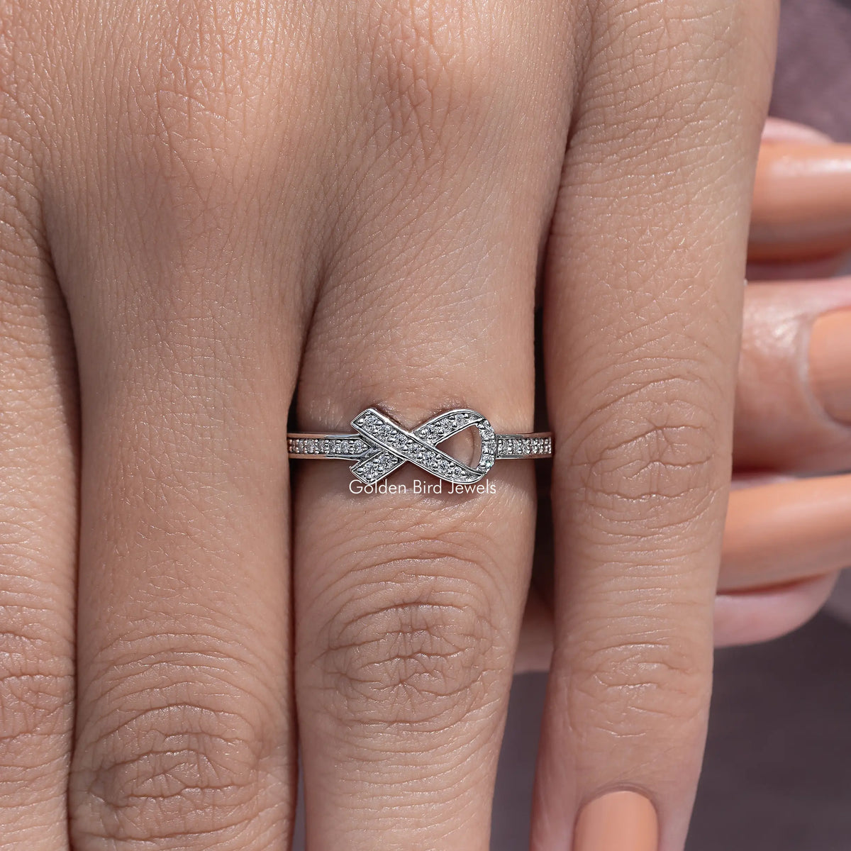 Silver hope ring featuring a bow-like cross motif with round-cut stones