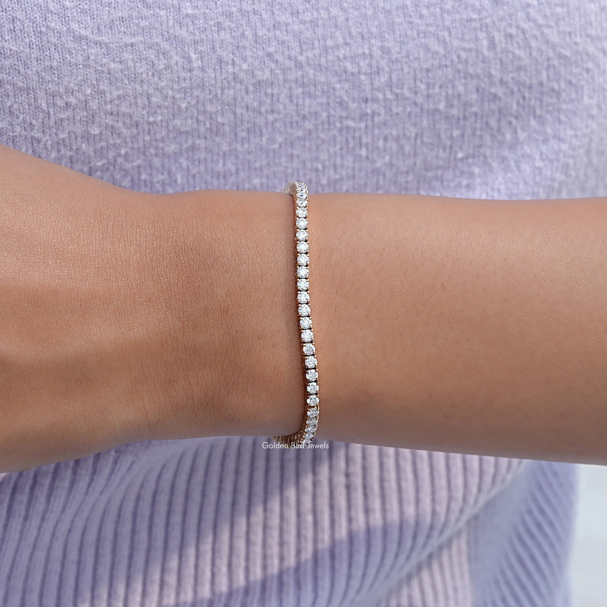 Round-cut stone tennis bracelet on forearm, delicate sparkle row