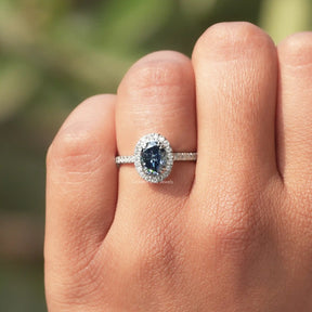 View of Blue Oval Cut Halo Engagement Ring In finger