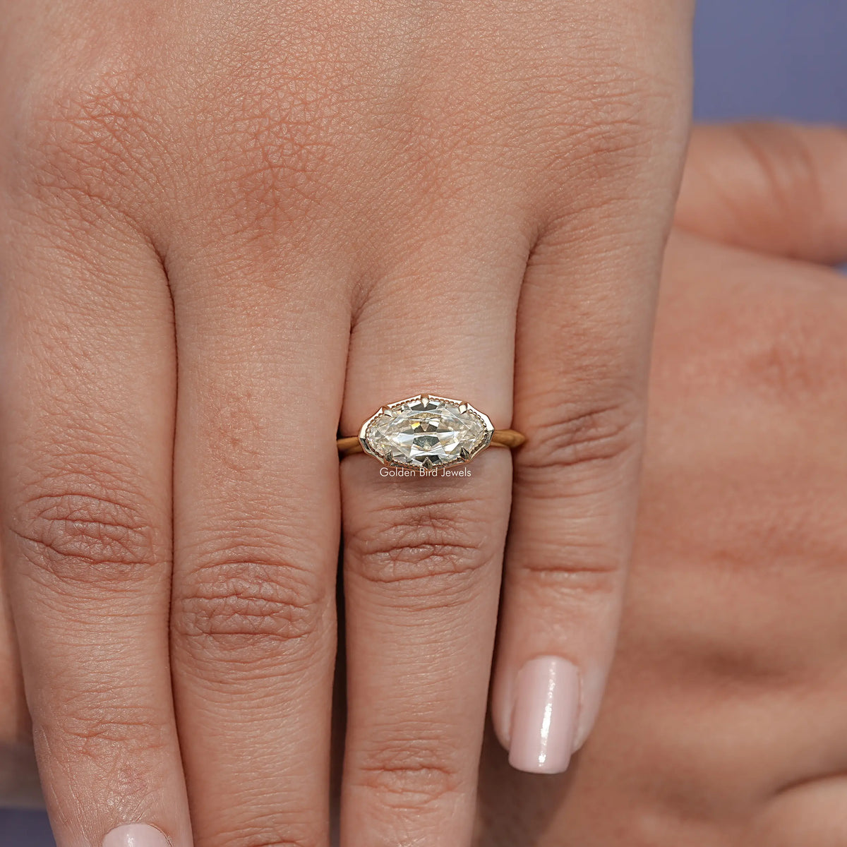 Gold-tone oval solitaire ring with faceted center stone, worn on hand