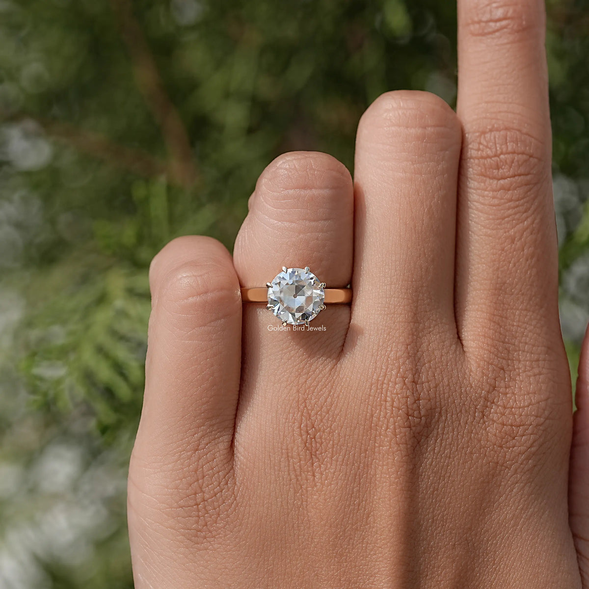 Round moissanite solitaire ring on hand, prong-set center stone with slim band