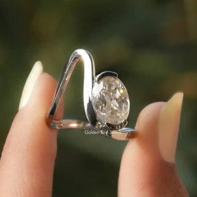 Two fingers holding the Solitaire Oval Cut Moissanite Curved Ring