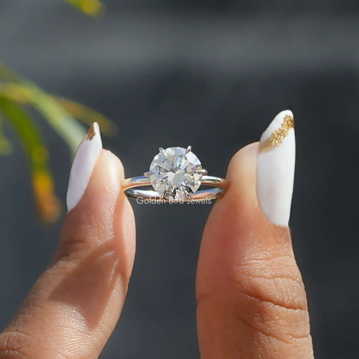 Two fingers holding the Round Cut Moissanite Solitaire Engagement Ring