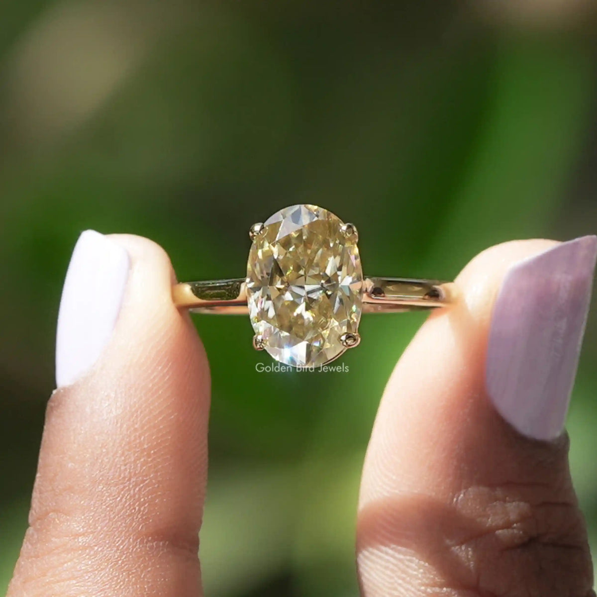 Two fingers holding the Solitaire Oval Cut Moissanite Engagement Ring