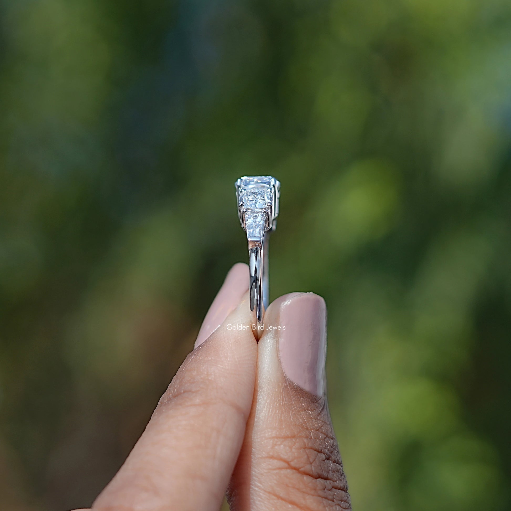 Side View of Cushion Cut Five Stone Engagement Ring In two fingers