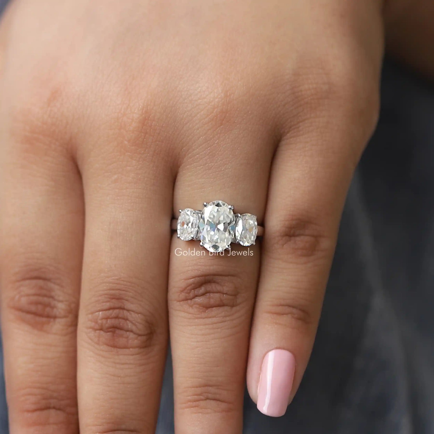 [In finger front view of three stone oval cut moissanite engagement ring]-[Golden Bird Jewels]
