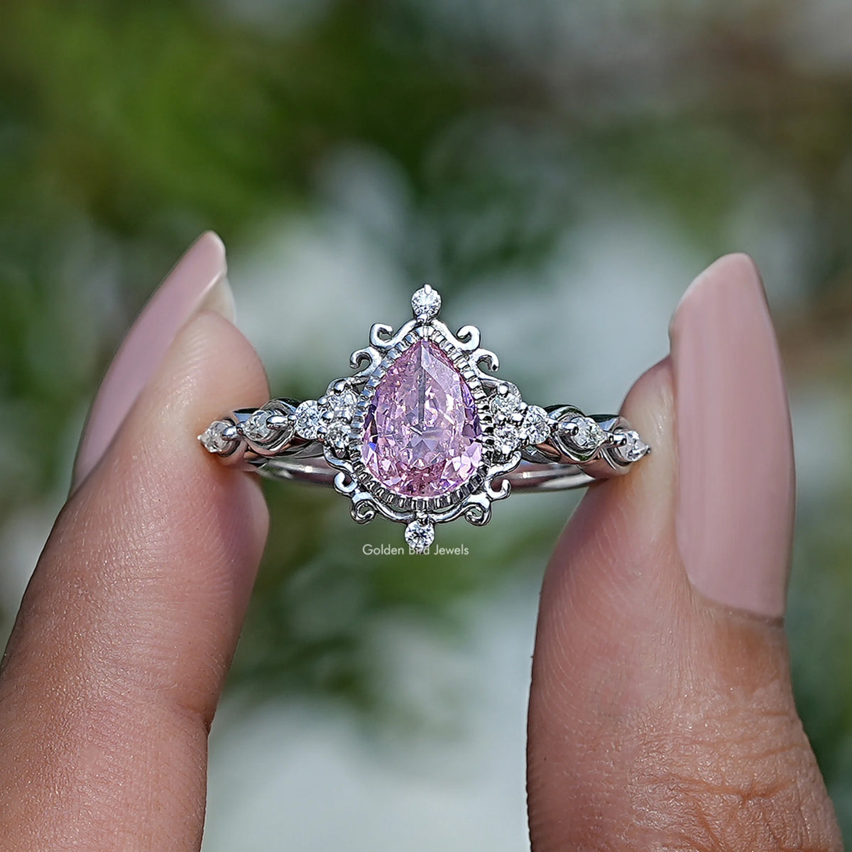 Two fingers holding the Pink Pear Cut Gemstone Ring