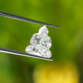 Close-up front view of tweezers holding a loose, Buddha Cut Moissanite in white