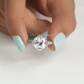 Front View of OEC Round Cut Vintage Moissanite Engagement Ring In two Fingers