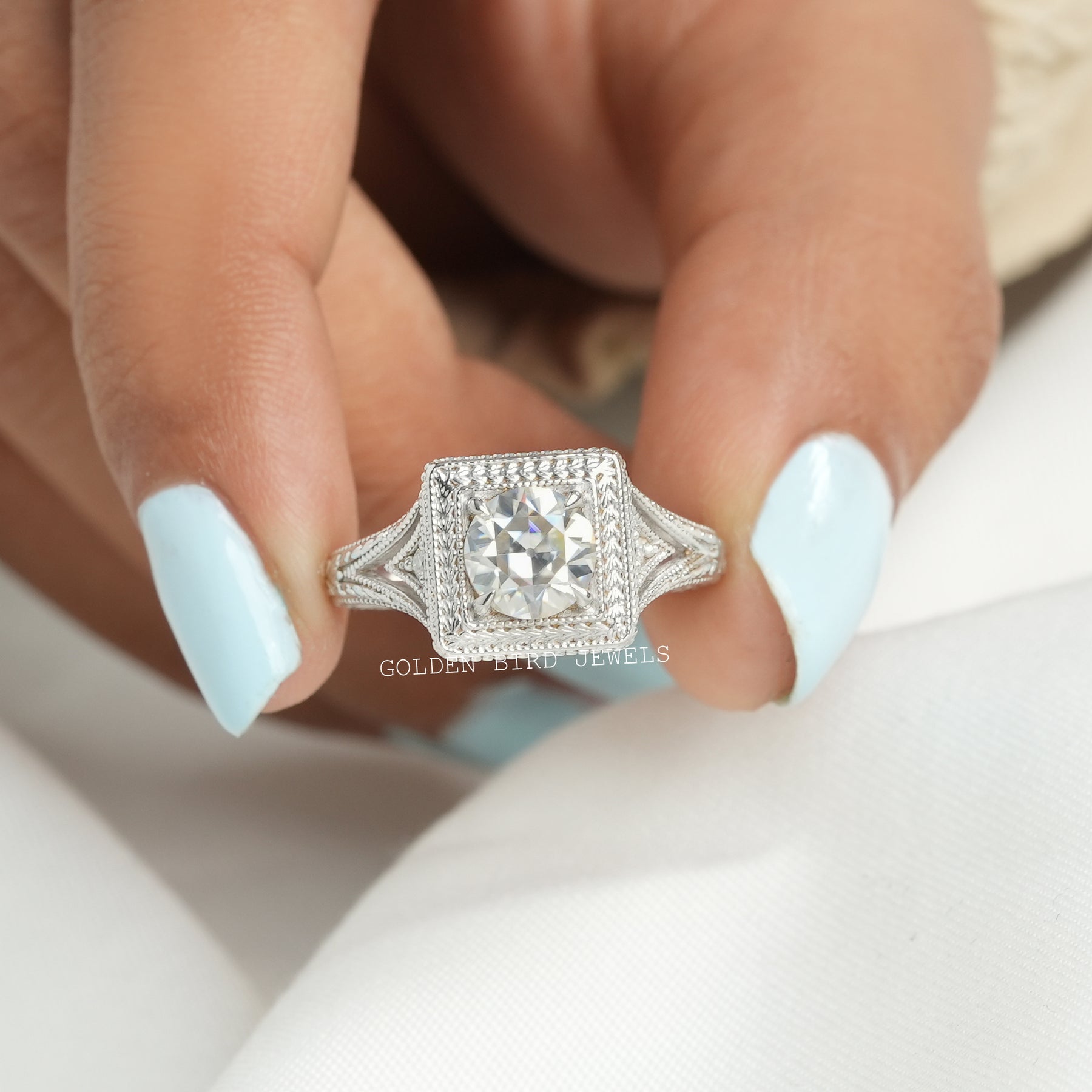 [In two finger front view of round cut moissanite ring made of 4 prongs]