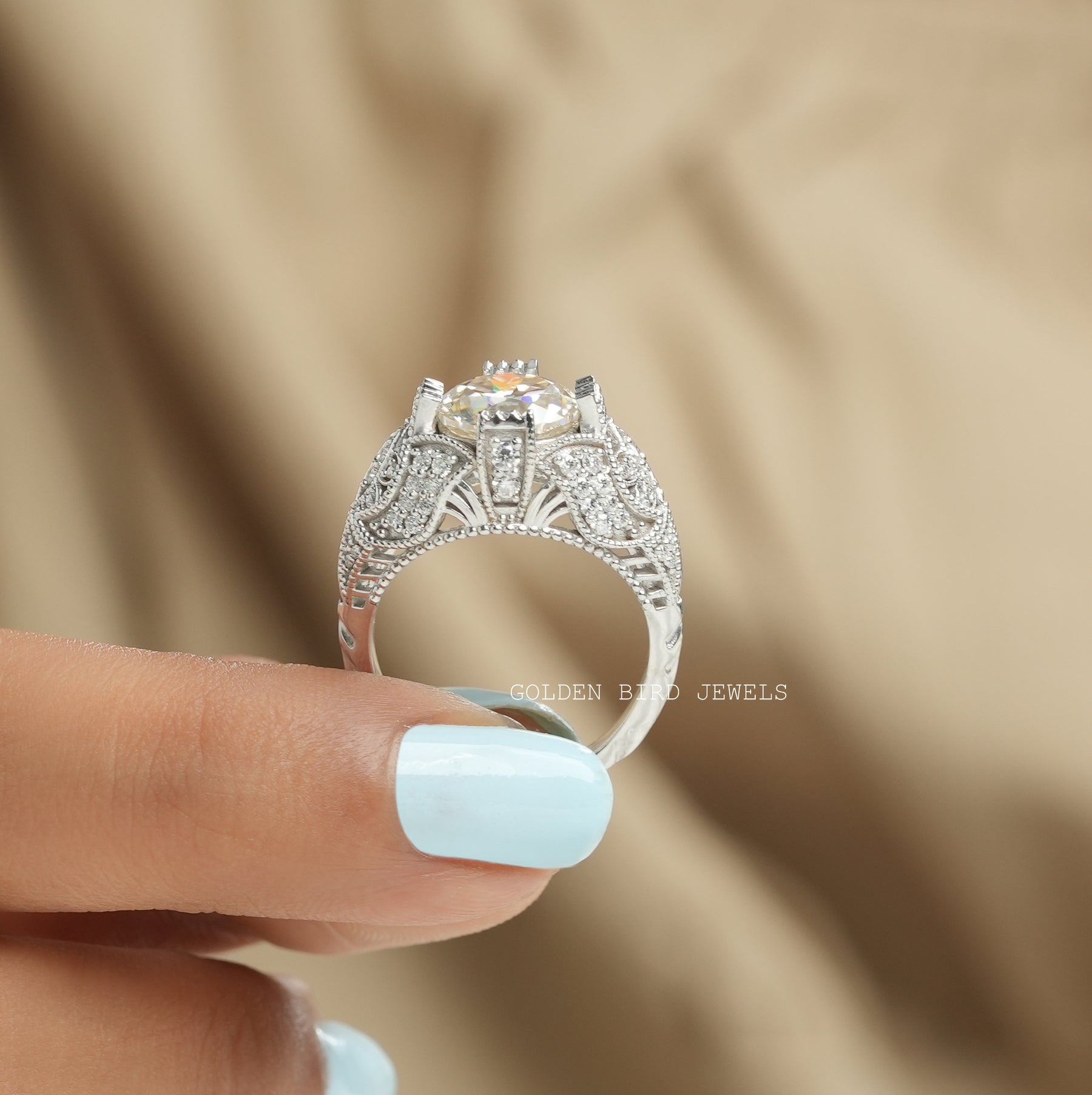 [A woman's hand holding art deco moissanite engagement ring with a colorless stone]-[Golden Bird Jewels]