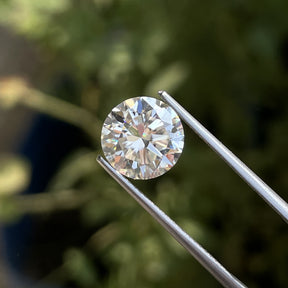 Tweezers holding the Moissanite Brilliant Round Cut Loose Stone