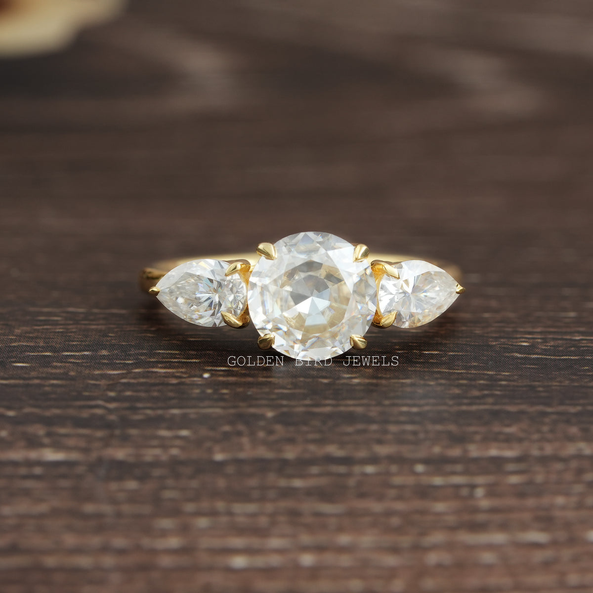 View of Round Cut Moissanite Three Stone Engagement Ring In Yellow Gold